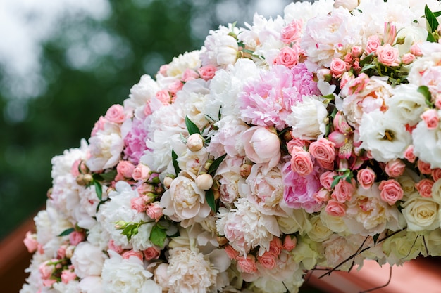 Arco redondo hecho de ramas de madera, decorado con muchas peonías y rosas. Florística de bodas de primavera en colores blanco y rosa, estilo rústico