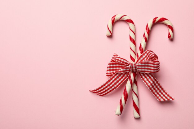 Arco de regalo a cuadros con bastones de caramelo sobre fondo rosa