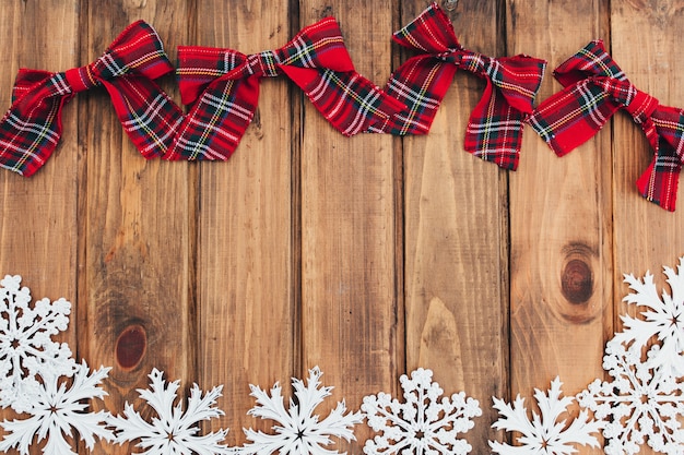 Arcos de Natal vermelho e flocos de neve brancos em madeira marrom.