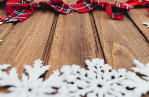 Foto arcos de natal vermelho e flocos de neve brancos sobre fundo de madeira marrom. foto de alta qualidade