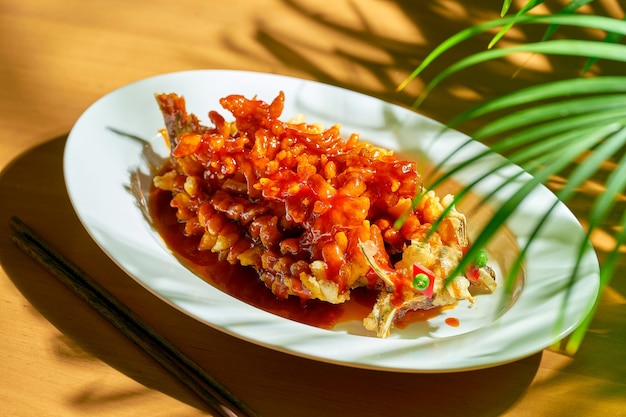 Ardilla de carpa de río frita o songshu yu en salsa agridulce con cilantro, semillas de sésamo y pimienta de Sichuan en un tazón blanco. cocina china