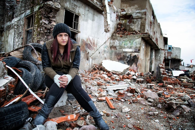 Foto Área de construção degradada de wrecke e jovem triste. ela perdeu tudo depois da guerra.