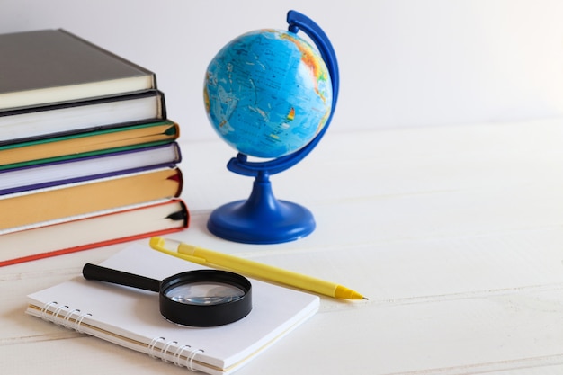 Foto Área de trabalho com livros, caderno, globo, caneta e lupa copiar espaço conceito de educação