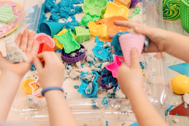 Areia cinética. as mãos das crianças brincam com areia polimérica multicolorida.