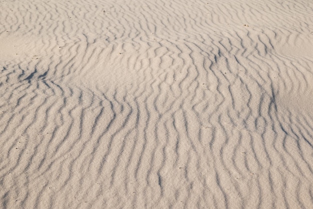 Foto areia com ondas na praia areia branca sob a luz do sol brilhante água e vento fizeram pequenas ondas sobre ele