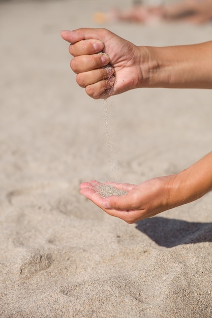 Areia correndo pelas mãos femininas como um símbolo de que o tempo está se esgotando