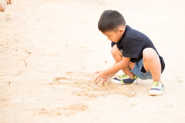 Areia de assento do menino no campo da areia.