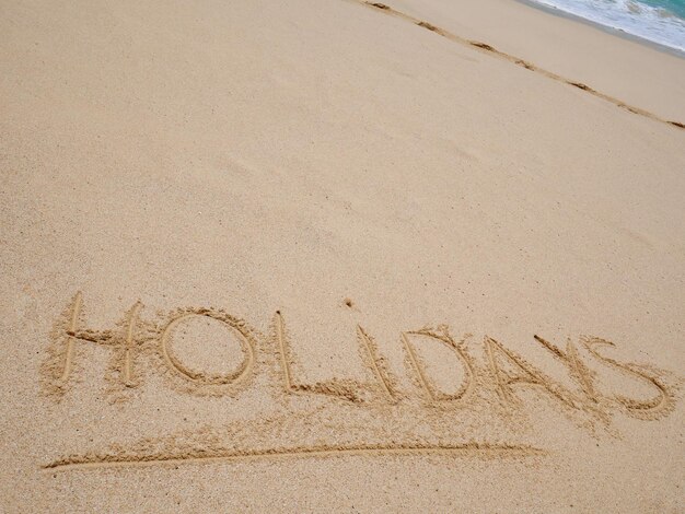 areia e sol fundo férias palavra escrita à mão em uma praia de areia
