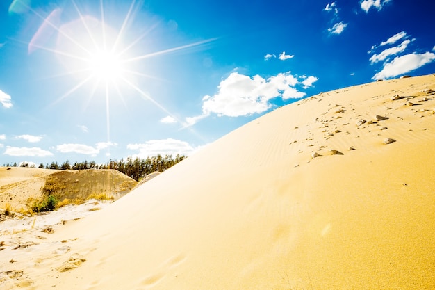 Areia iluminada pelo sol brilhante do meio-dia no céu azul