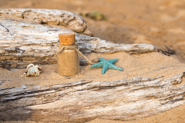 en la arena en una botella de arena de mar, una concha y una estrella de mar al lado