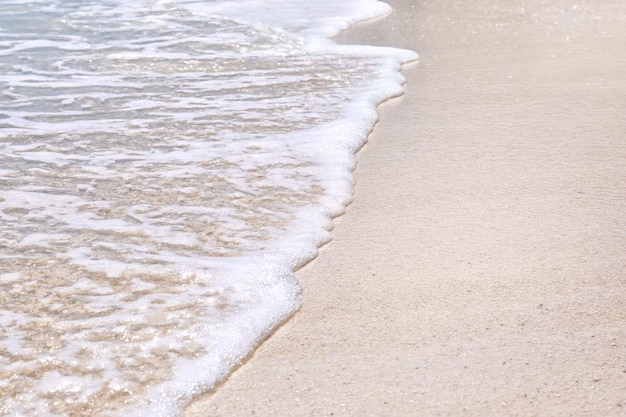 Arena cálida y olas de mar en la playa en el primer plano del resort