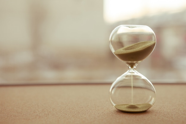 Arena corriendo a través de las bombillas de un reloj de arena que mide el tiempo que pasa en una cuenta regresiva para una fecha límite