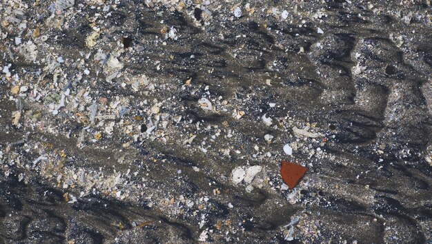 arena de mar y pequeñas piedras llevadas por las olas a la playa
