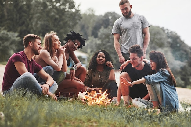 Arena y pasto. Grupo de personas tienen picnic en la playa. Los amigos se divierten los fines de semana.