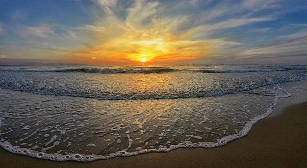 Arena en la playa y mar ondulante en el fondo del cielo pintoresco al atardecer