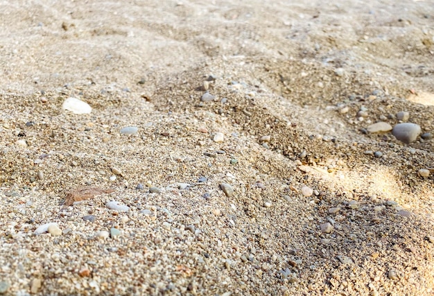 Arena en la playa con piedras y tierra costa del mar pequeña dispersión de piedras arena caliente cerca