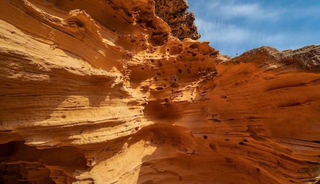 Areniscas anaranjadas erosionadas en la orilla de una playa