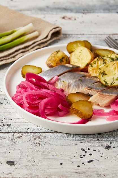 Foto arenque com cebola de batata assada e pepino em conserva closeup