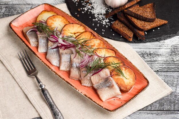 Arenque con patatas pescado aperitivo sobre un fondo blanco de madera