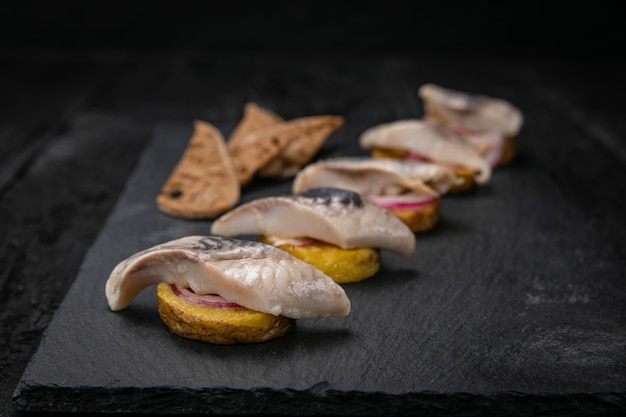 arenque con picatostes y patatas en una mesa oscura