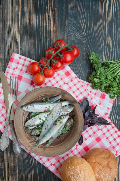 Arenque salado en un recipiente con especias y hierbas. Mariscos. Pescado salado con especias. Platos de pescado. Fondo de madera oscura Copia espacio Menú de fondo de la tabla.