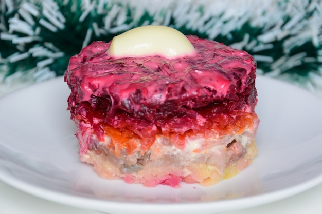 Arenque vestido o arenque debajo de un abrigo de piel. Símbolo del año nuevo. Cocina tradicional rusa. Adornos navideños en el fondo. Concepto de año nuevo.