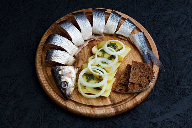 Arenques salados con patatas hervidas y salsa verde.