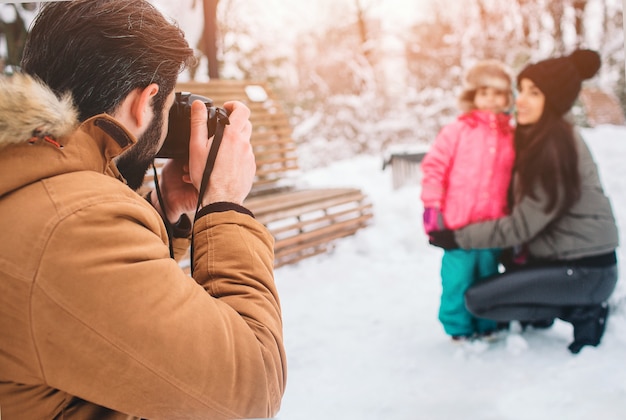 Arenthood, forma, estação e conceito dos povos - a família feliz com a criança no inverno veste-se fora. tire fotos uns com os outros