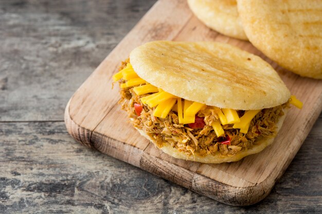 Arepa mit zerkleinertem Rindfleisch und Käse auf venezolanischem typischen Holztisch