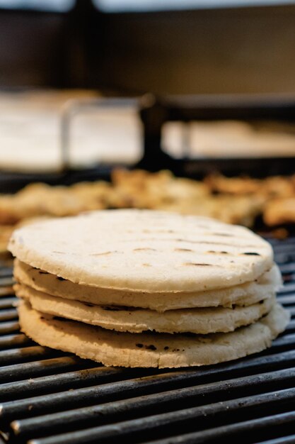 Arepas paisas apiladas cocinadas sobre carbón en una parrilla foto vertical de arepa colombiana