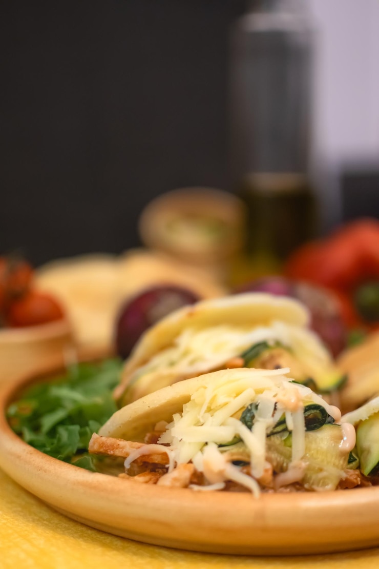 Arepas tradicionales originarias de América Latina masa de maíz rellena sabrosa con fondo amarillo claro y verduras típicas