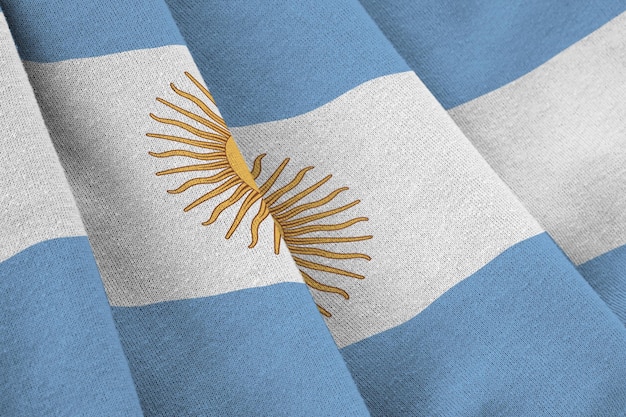 Argentinien-Flagge mit großen Falten, die in der Nähe unter dem Studiolicht im Innenbereich winken Die offiziellen Symbole und Farben im Banner