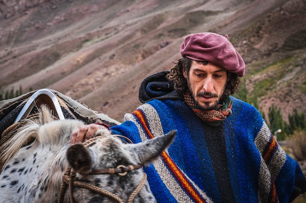 Argentinischer Gaucho mit seinen Pferden, heißes Getränk trinkend.