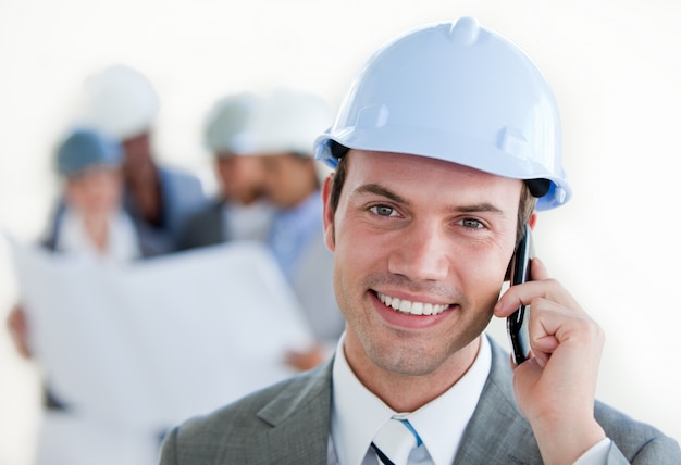 Arhitect sonriente con un casco en el teléfono