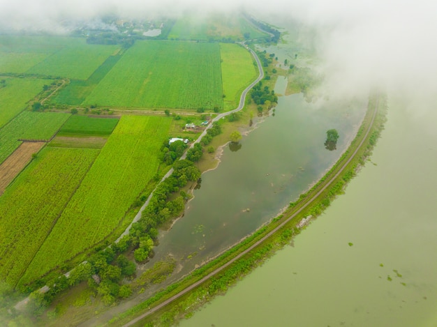 Arial-Ansicht von den Wolken der Eisenbahnbrücke über dem See mit Ackerland neben dem See