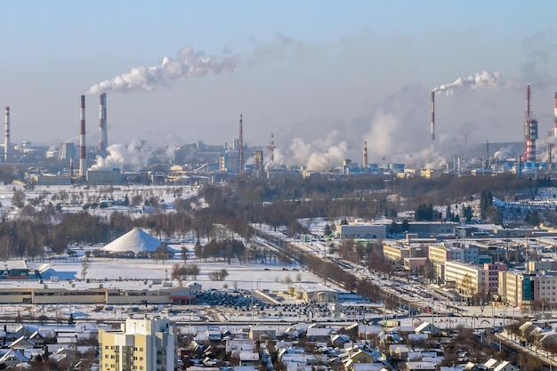 Ariel Panoramablick auf die Stadt und die Wolkenkratzer mit einer riesigen Fabrik mit rauchenden Schornsteinen im Hintergrund