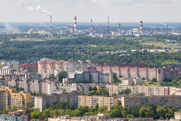 Ariel vista panorámica de la ciudad y los rascacielos con una enorme fábrica con chimeneas humeantes en el fondo