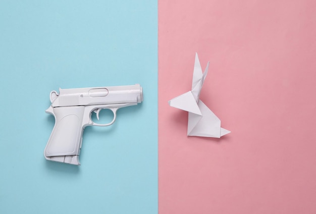 Arma branca com coelho de origami em fundo rosa azul layout criativo mínimo dizer não a guerra