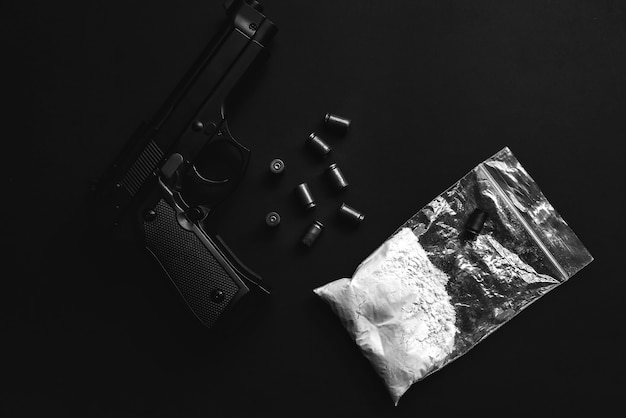 Foto arma com balas em cima da mesa. problemas criminais. drogas no pacote. venda ilegal. foto em preto e branco.