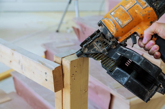 Arma de construcción dispara las uñas del muro de madera.