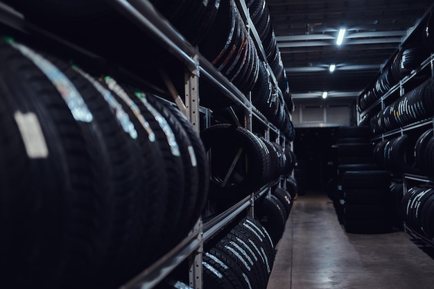 Armazenamento escuro cheio ou grande variedade de pneus novos em armazém movimentado.