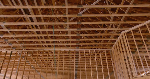 Foto armazón de vigas de techo de madera en una casa construida con palos en construcción que enmarca una vista interior