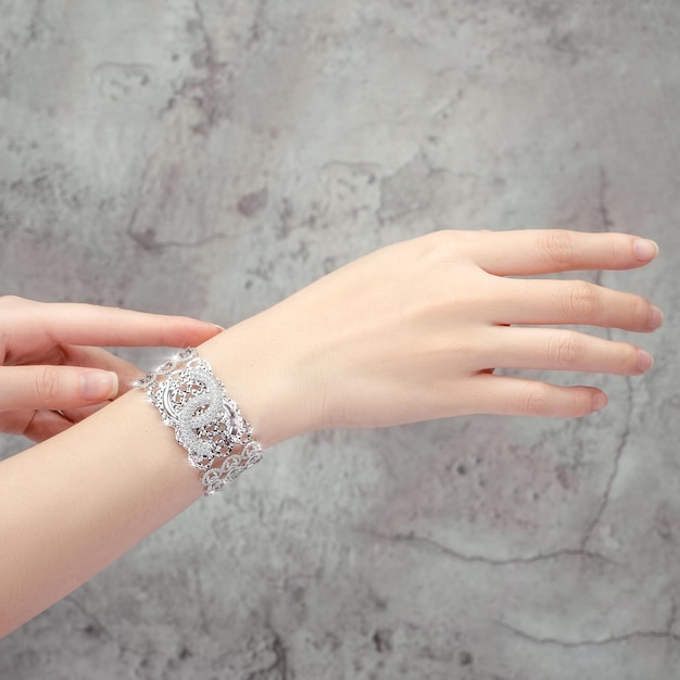Armband eingelegt mit einem Diamanten auf der Hand isoliert auf grauem Hintergrund