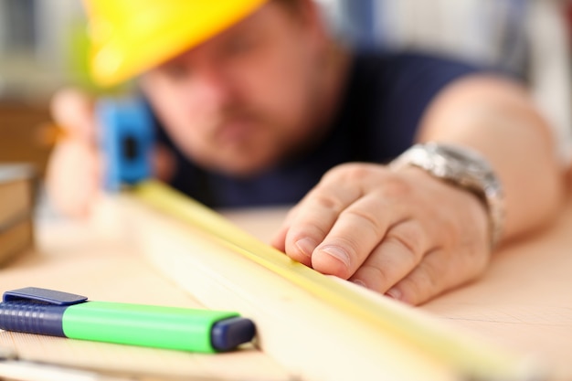 Arme des Arbeiters, der Holzstangen-Nahaufnahme misst