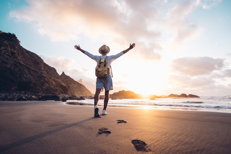 Foto arme des jungen mannes, die bei sonnenaufgang vom meer ausgestreckt werden und freiheit und leben genießen, reisen menschen wohlbefinden konzept