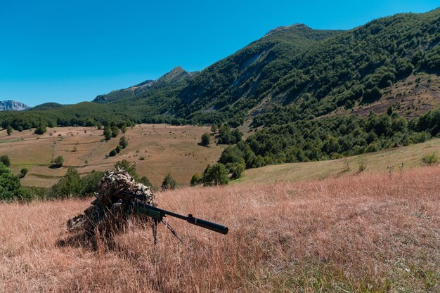 Armeesoldat hält Scharfschützengewehr mit Zielfernrohr und zielt im Wald. Konzept für Krieg, Armee, Technologie und Menschen.