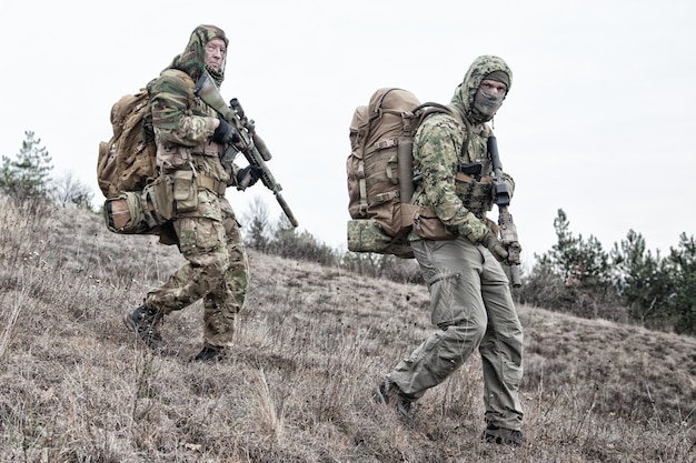 Armeeteammitglieder, militärische Söldnergruppe in verschiedenen Tarnuniformen, bewaffnete Dienstgewehre, Beobachtung des Territoriums vom Hügel, Patrouillengebiet während der Mission