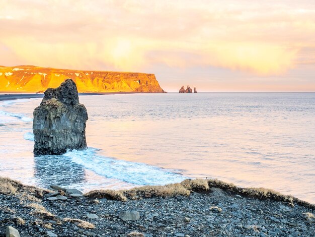 Arnardrangur en la costa cerca del arco Dyrholaey que rodea la montaña de olas pesadas al sur de Islandia