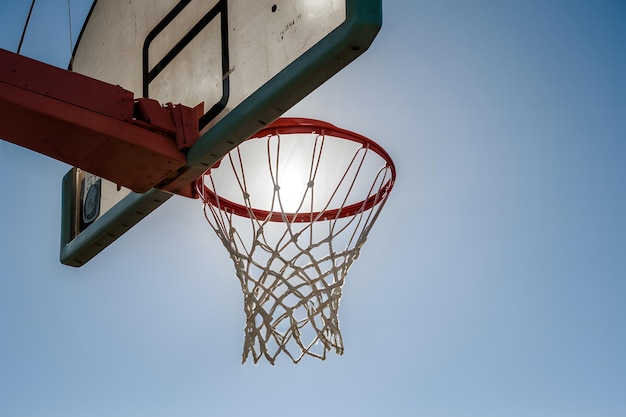 El aro de baloncesto iluminado por el sol significa un juego deportivo intenso