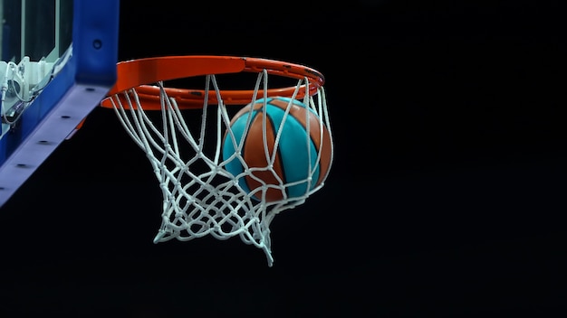 Aro de baloncesto con una red en la que la pelota vuela sobre un fondo oscuro